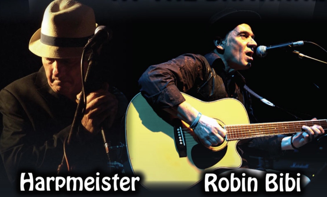 Robin Bibi singing and playing acoustic guitar alongside harmonica player Harpmeister on stage